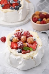 Photo of Pavlova cake (meringue dessert) with whipped cream, fresh berries, powdered sugar and mint on table, closeup