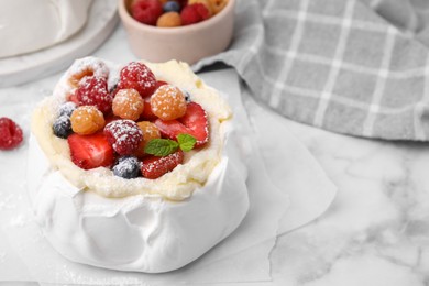 Photo of Pavlova cake (meringue dessert) with whipped cream, fresh berries, powdered sugar and mint on white marble table, closeup