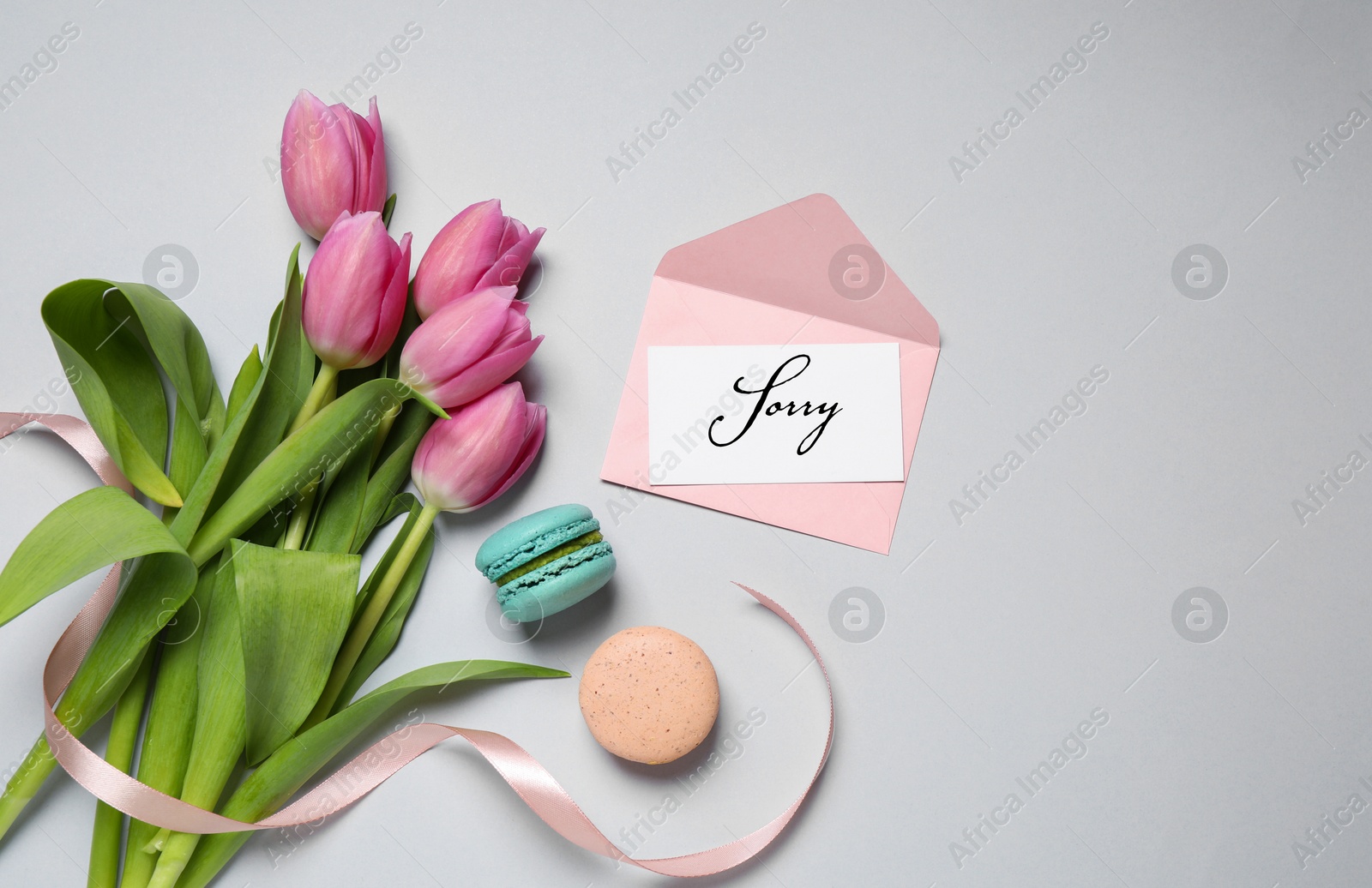 Image of Sorry card, envelope, macarons and pink tulips on light grey table, flat lay. Space for text