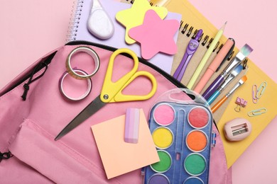 Photo of Backpack and different school stationery on pink background, top view