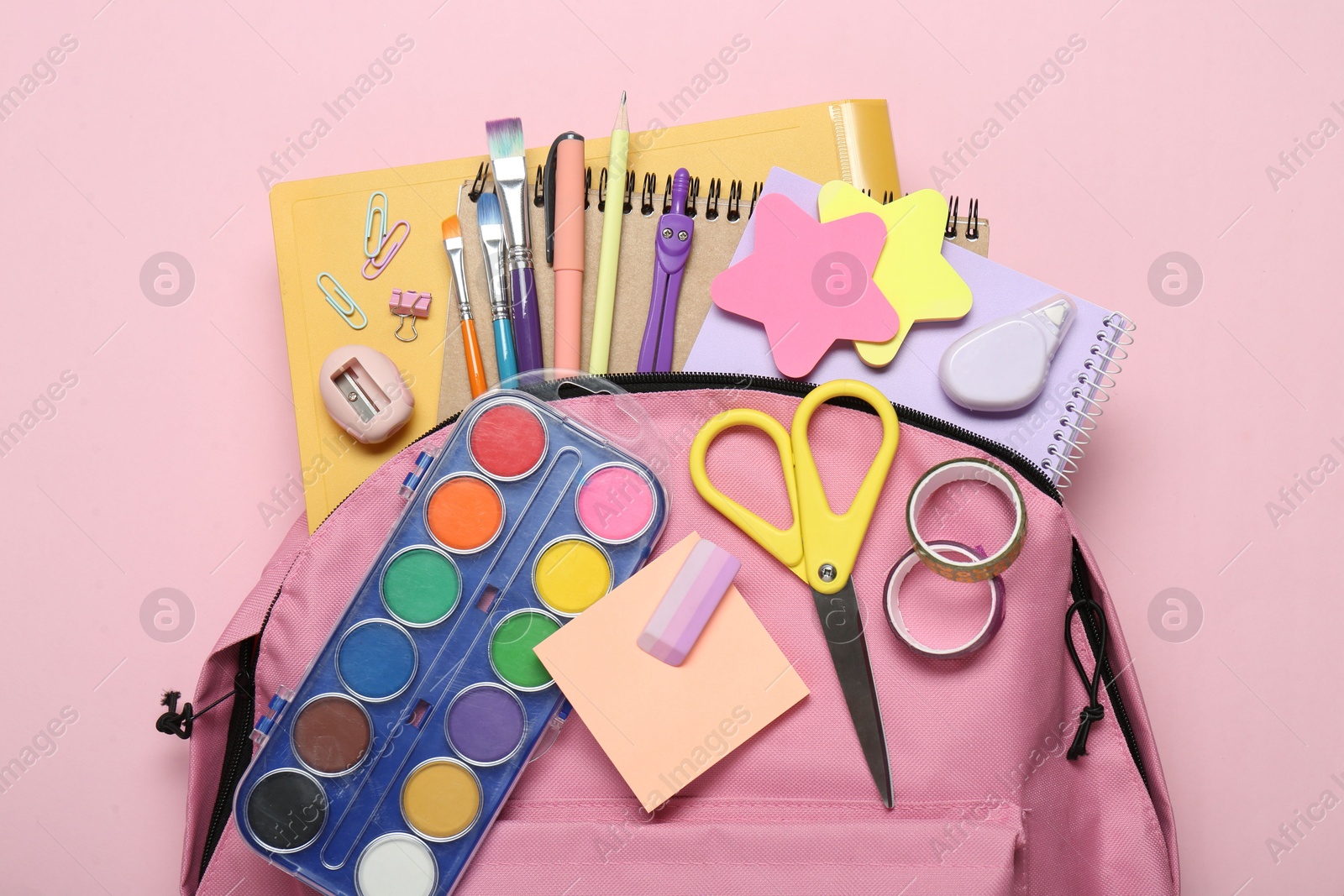 Photo of Backpack and different school stationery on pink background, top view