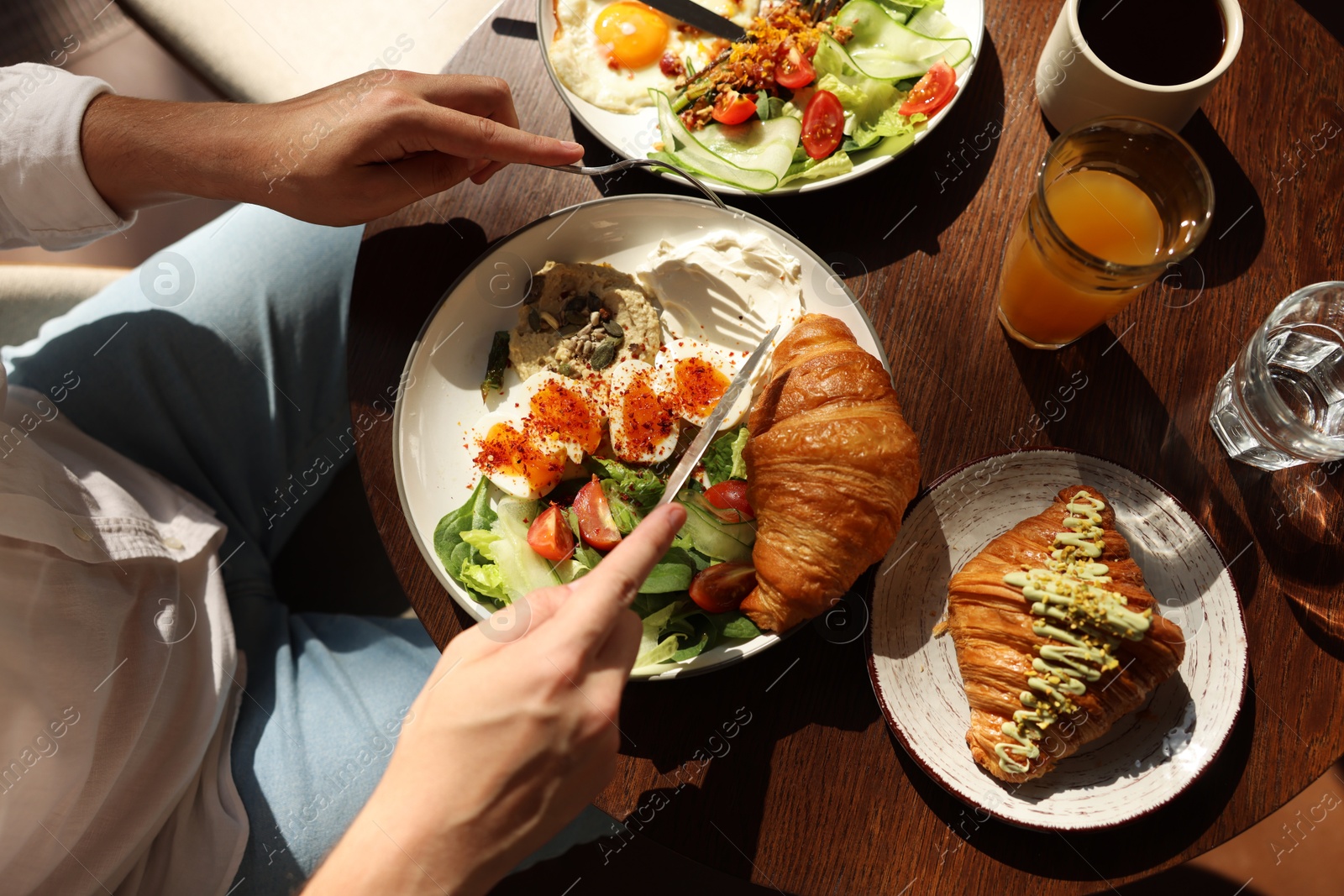 Photo of Man having tasty breakfast at wooden table in cafe, top view