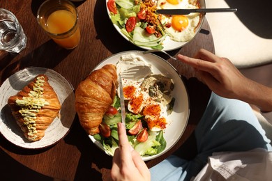 Man having tasty breakfast at wooden table in cafe, top view