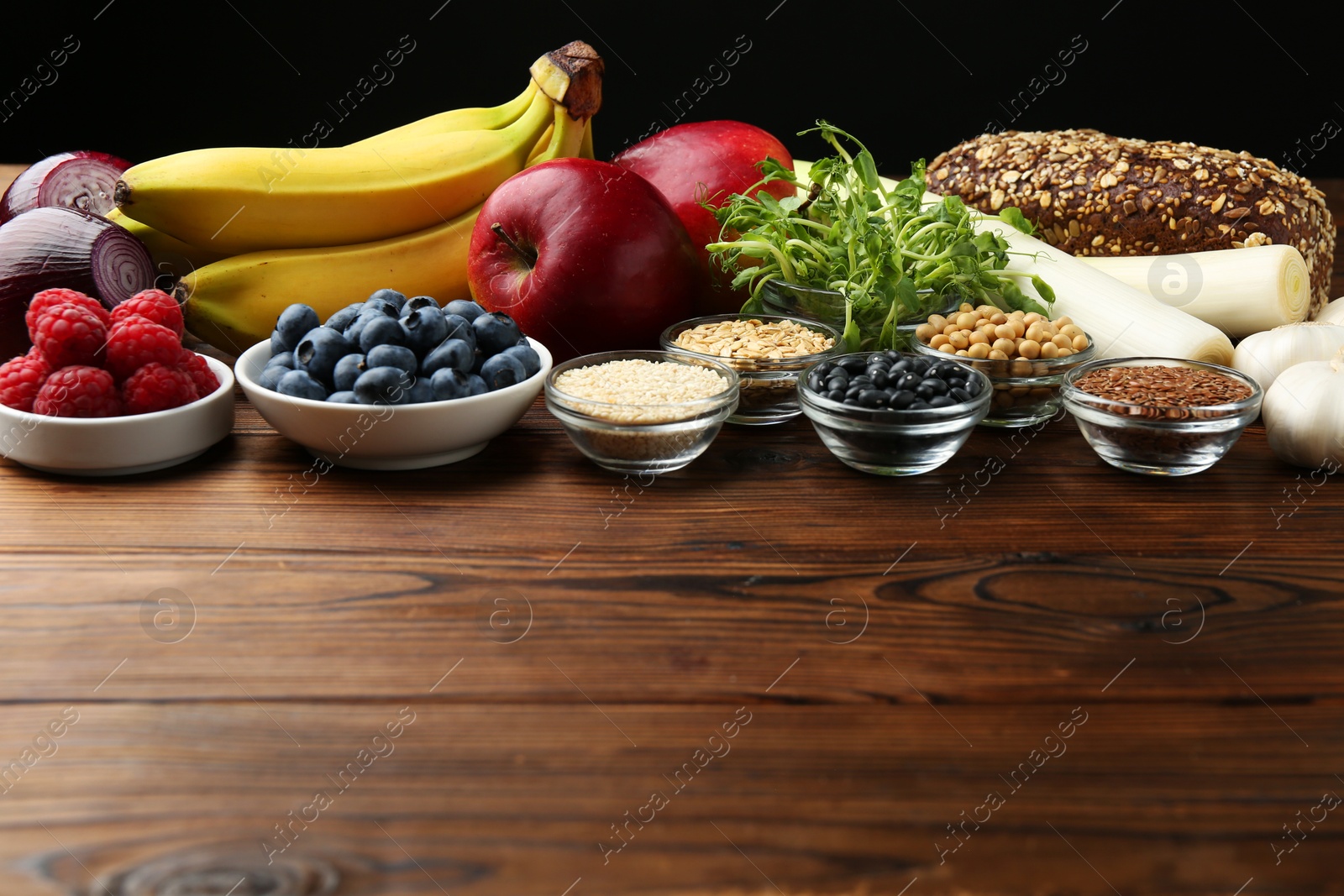 Photo of Different fresh products on wooden table, space for text. Source of prebiotics