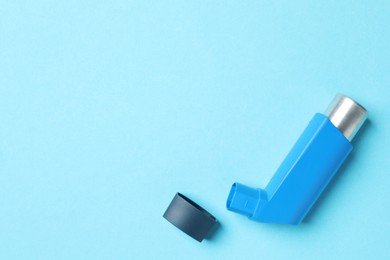 Photo of Asthma inhaler on light blue background, top view. Space for text