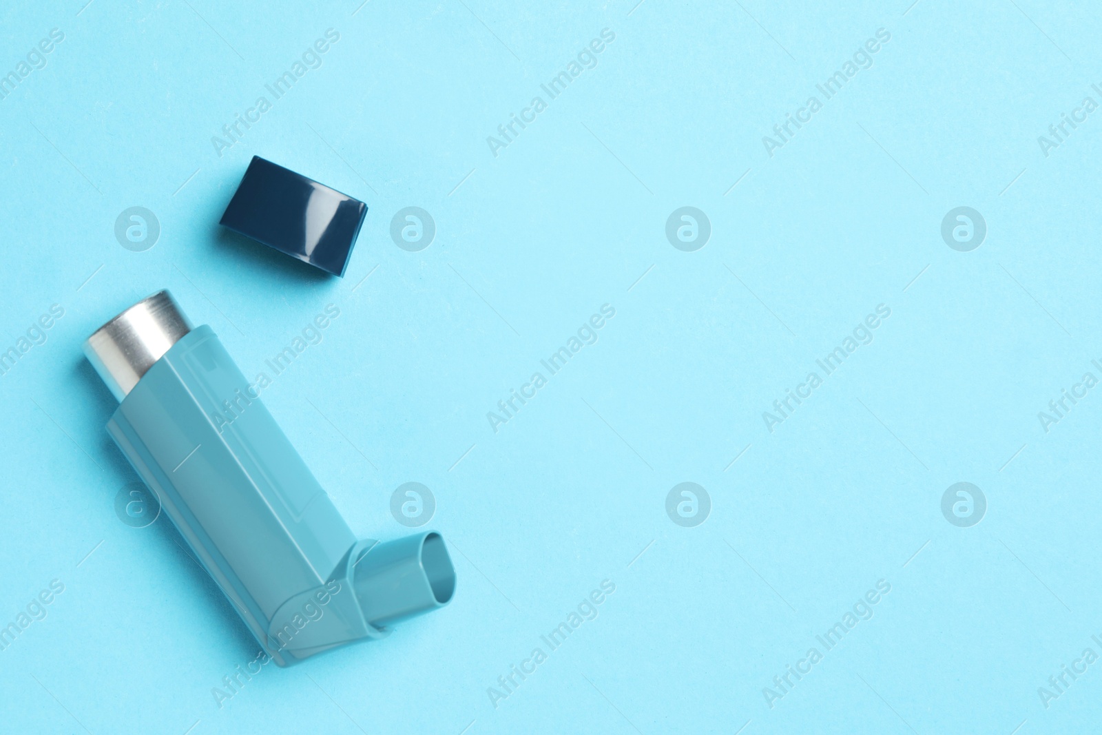 Photo of Asthma inhaler on light blue background, top view. Space for text