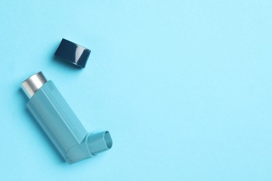 Photo of Asthma inhaler on light blue background, top view. Space for text