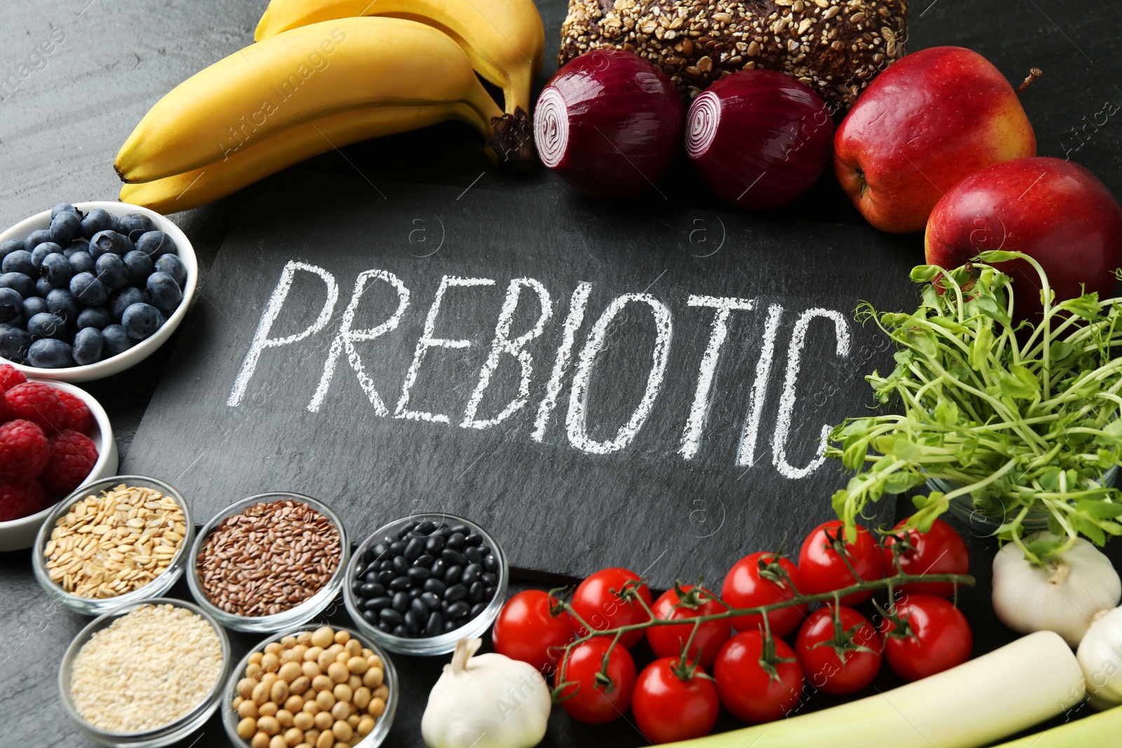 Photo of Slate board with word Prebiotic and different fresh products on black table