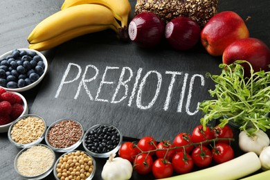 Photo of Slate board with word Prebiotic and different fresh products on black table