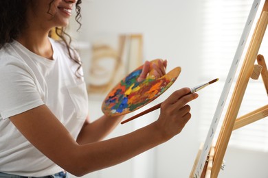 Photo of Smiling woman drawing picture with paint in studio, closeup