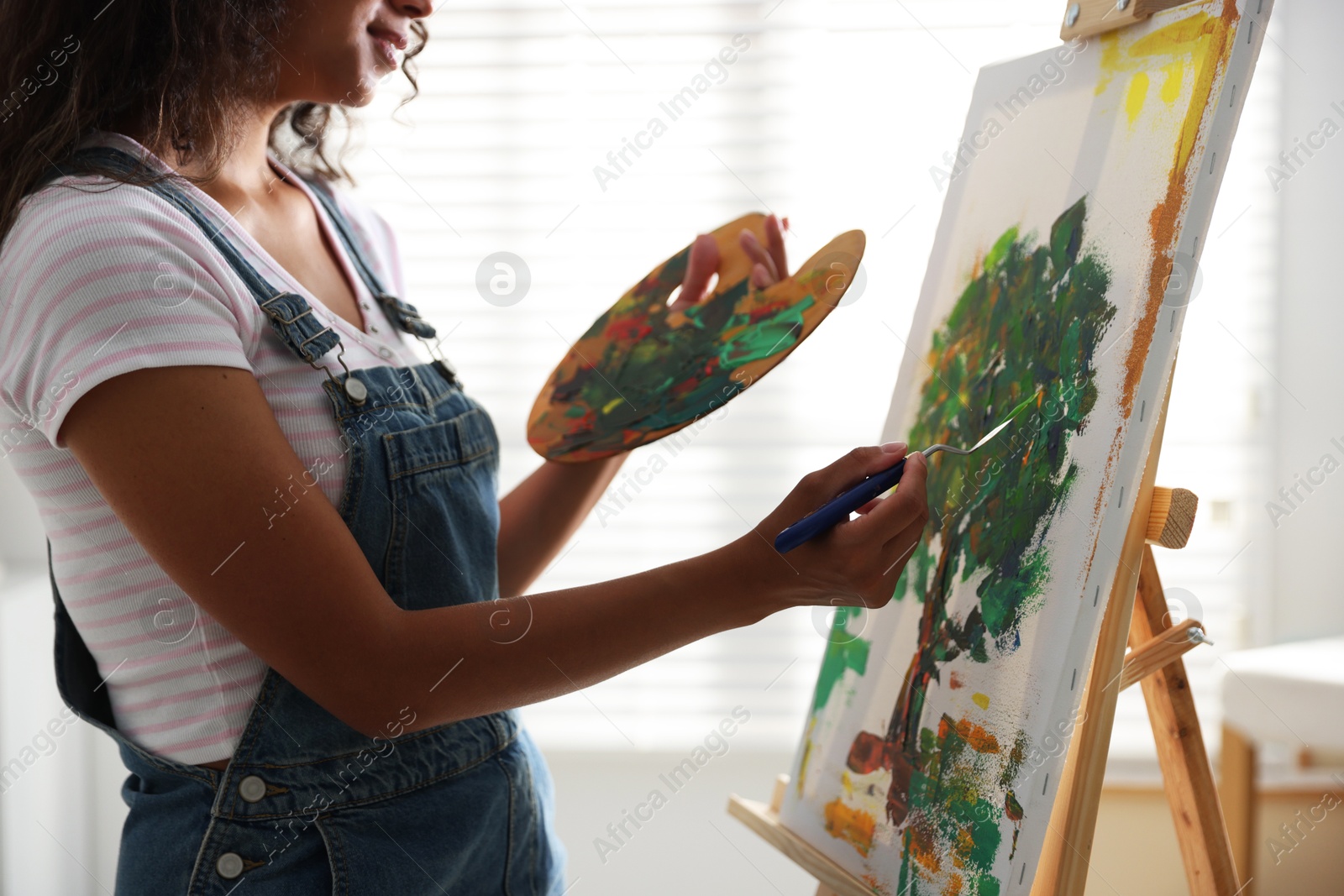 Photo of Woman drawing picture with palette knife in studio, closeup