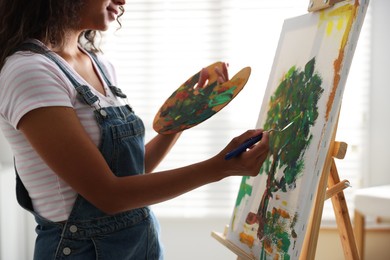 Woman drawing picture with palette knife in studio, closeup