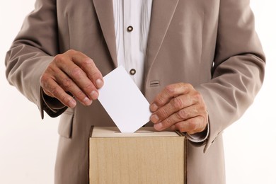 Referendum. Man putting his vote into ballot box against white background, closeup