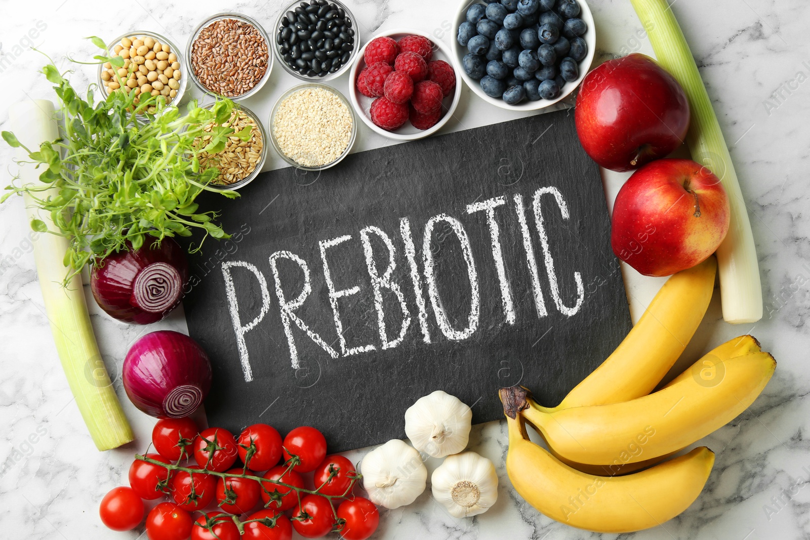 Photo of Slate board with word Prebiotic and different fresh products on white table, flat lay