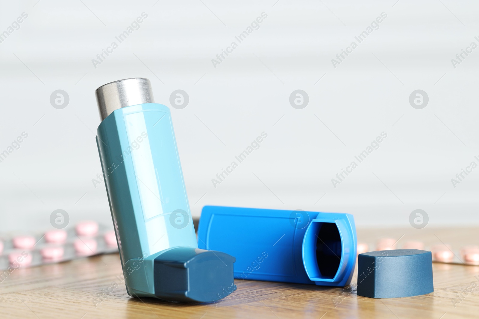 Photo of Inhalers on wooden table indoors, closeup with space for text. Asthma treatment