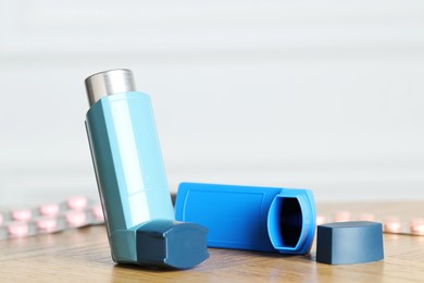 Photo of Inhalers on wooden table indoors, closeup with space for text. Asthma treatment