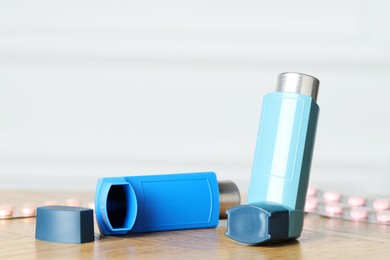 Photo of Inhalers on wooden table indoors, closeup with space for text. Asthma treatment