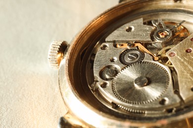 Photo of Mechanism of vintage wrist watch on beige background, closeup