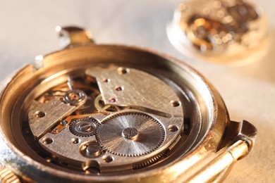 Photo of Mechanism of vintage wrist watch on beige background, closeup