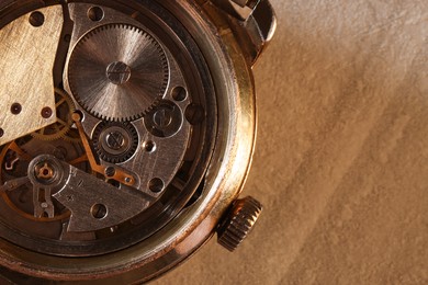 Photo of Mechanism of vintage wrist watch on beige table, top view. Space for text