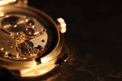 Photo of Mechanism of vintage wrist watch on black background, closeup. Space for text