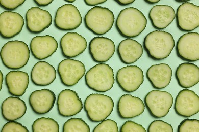 Photo of Slices of fresh cucumbers on turquoise background, flat lay