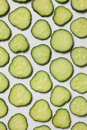 Photo of Slices of fresh cucumbers on white background, flat lay