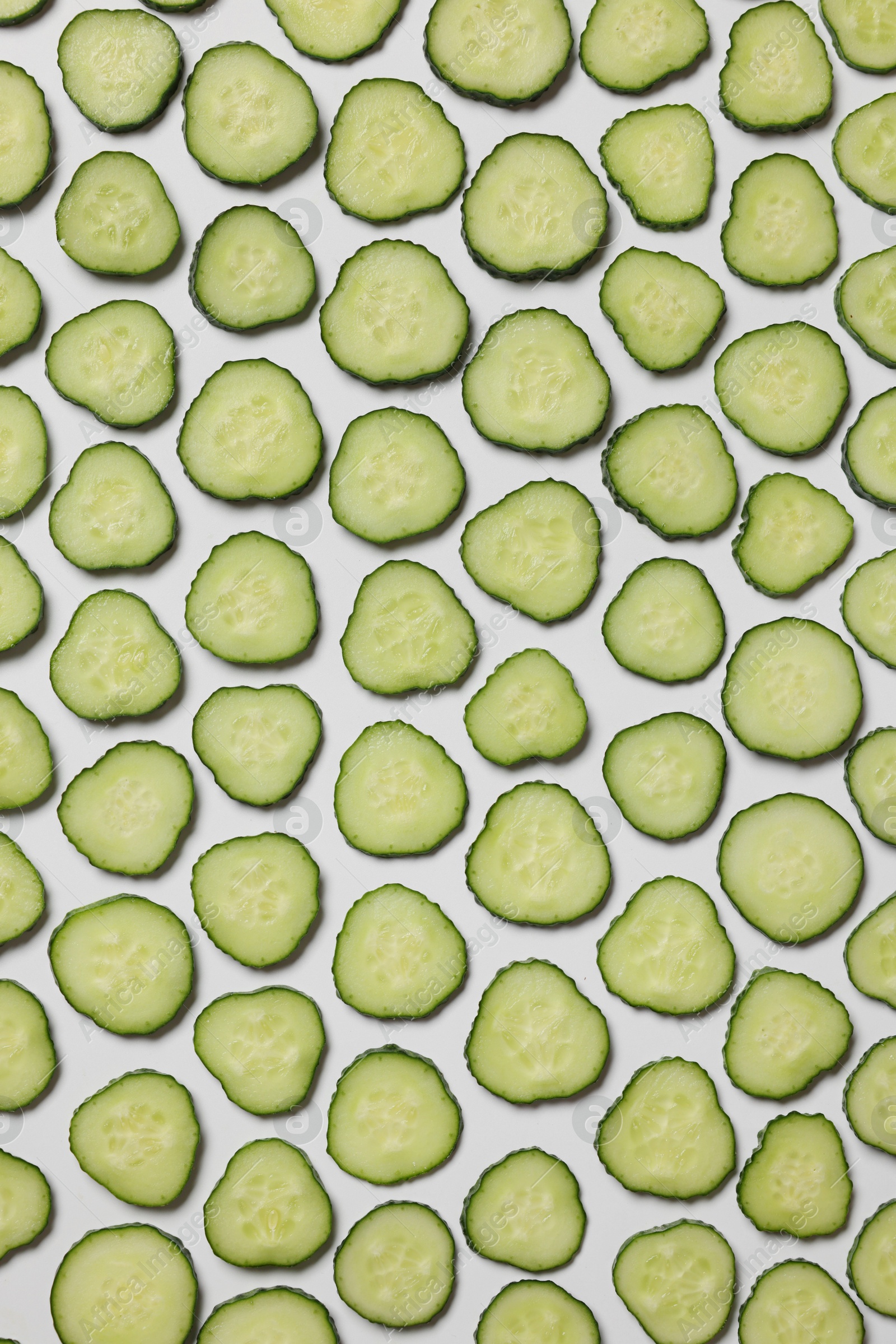 Photo of Slices of fresh cucumbers on white background, flat lay