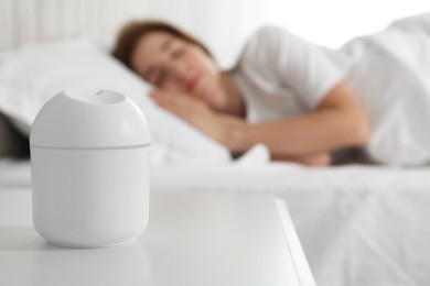 Photo of Woman sleeping at home, focus on essential oil aroma diffuser