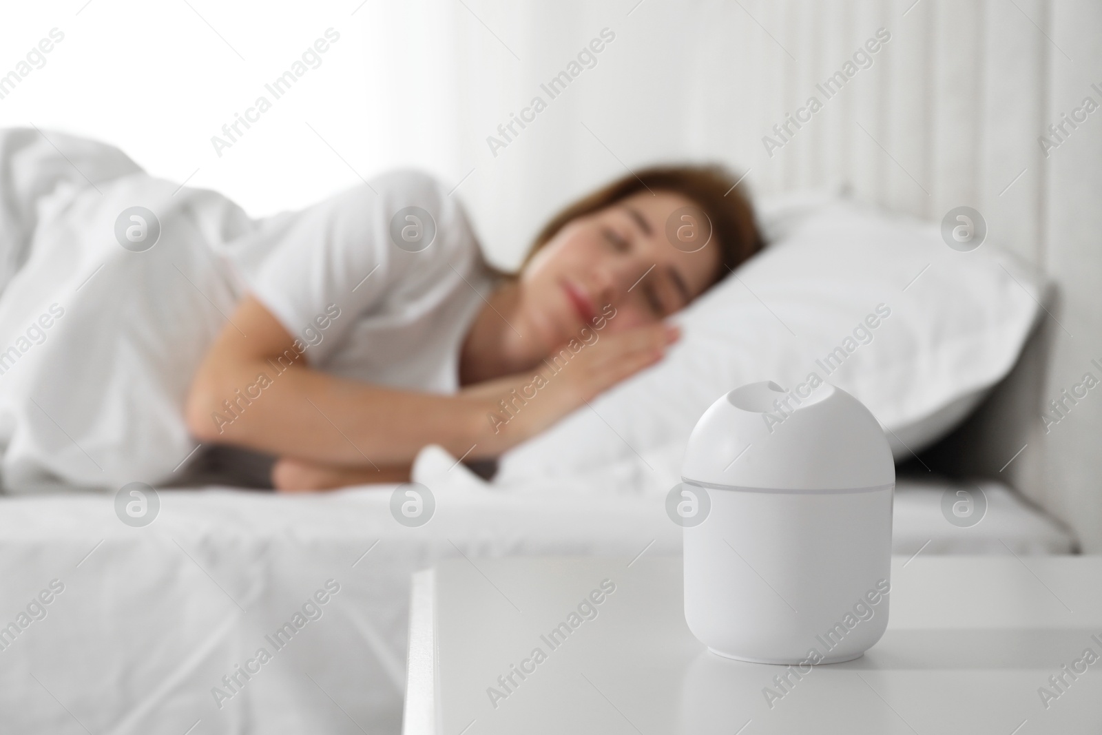 Photo of Woman sleeping at home, focus on essential oil aroma diffuser