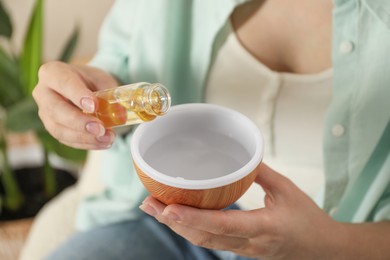 Photo of Woman adding essential oil to aroma diffuser at home, closeup