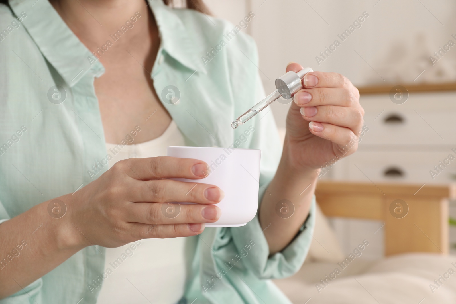 Photo of Woman adding essential oil to aroma diffuser at home, closeup