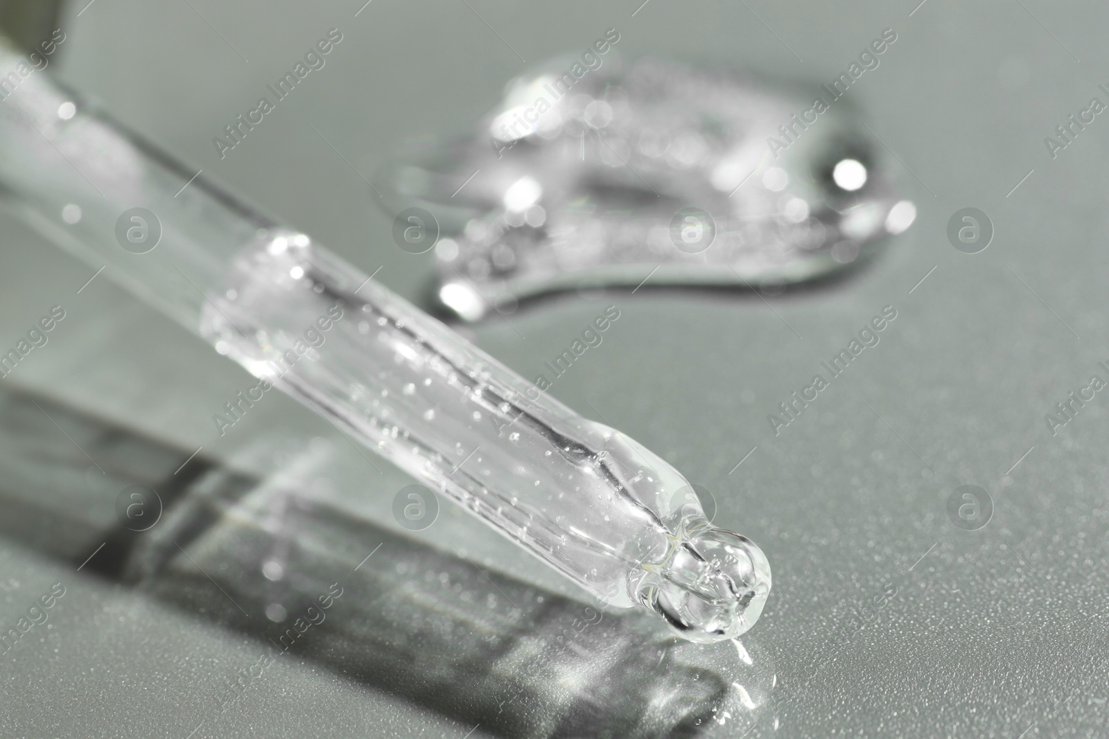 Photo of Pipette with cosmetic serum on grey background, closeup