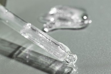 Pipette with cosmetic serum on grey background, closeup