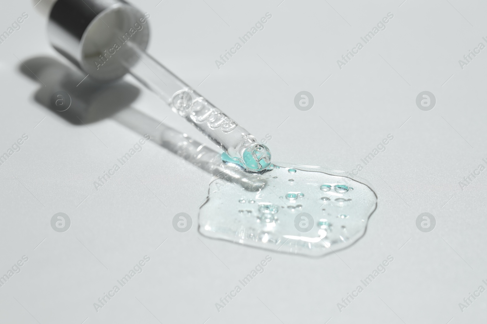 Photo of Pipette with cosmetic serum on light background, closeup