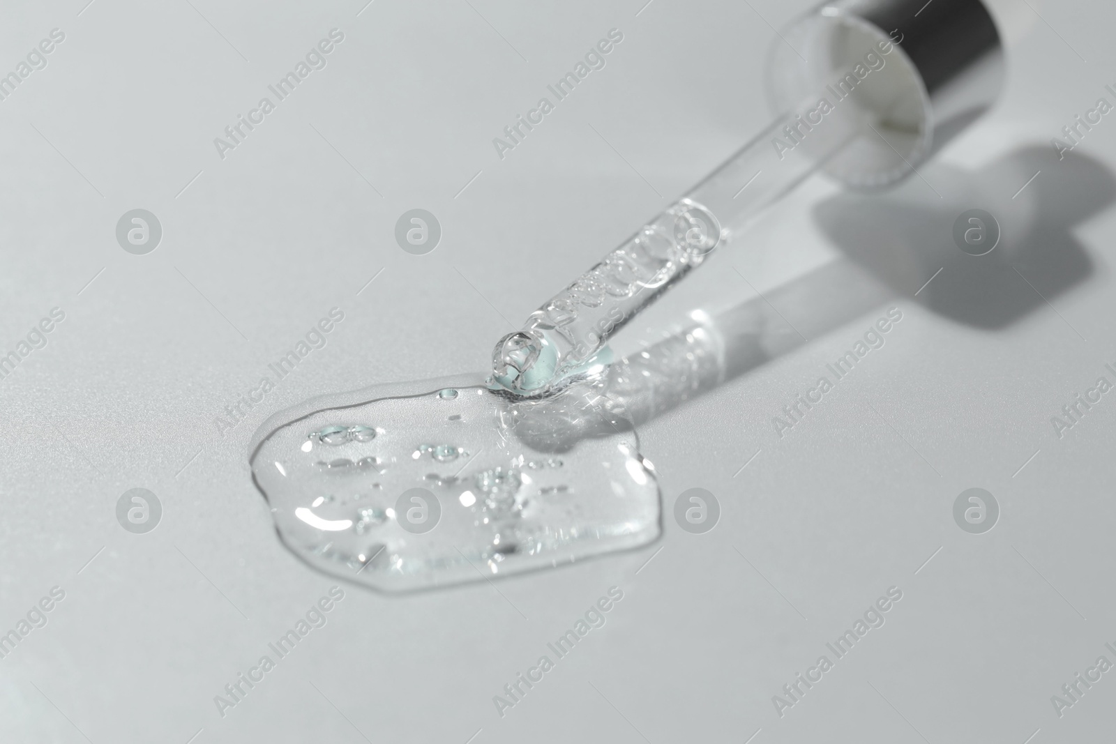 Photo of Pipette with cosmetic serum on light background, closeup