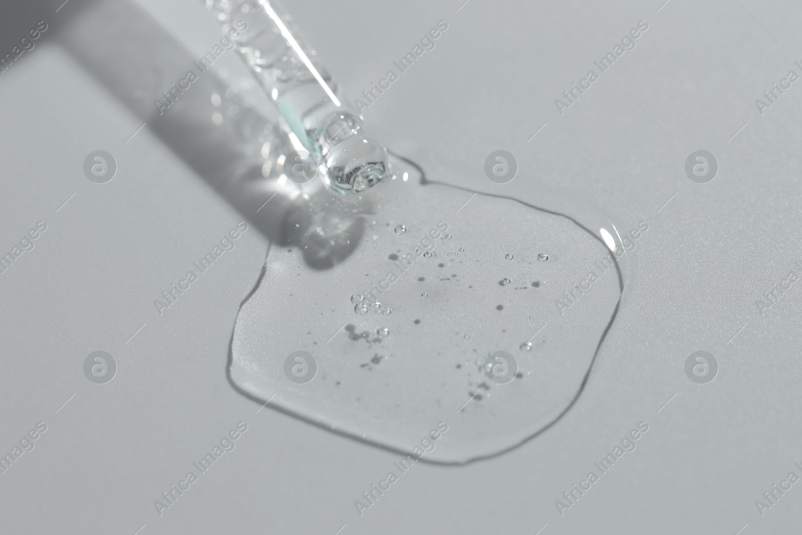 Photo of Pipette with cosmetic serum on light background, closeup