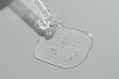 Photo of Pipette with cosmetic serum on light background, closeup