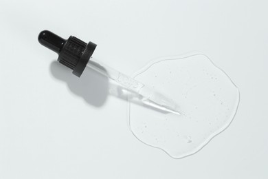 Photo of Pipette with cosmetic serum on light background, top view