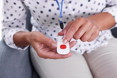 Senior woman pressing emergency call button at home, closeup