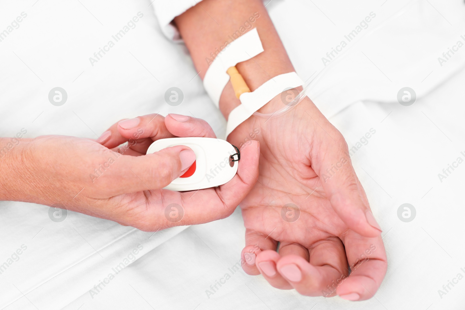 Photo of Senior woman pressing emergency call button on bed in hospital, top view