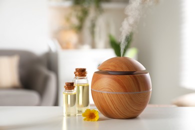 Photo of Essential oil diffuser, cosmetic products and calendula flower on white table at home