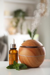 Photo of Essential oil diffuser, cosmetic product and mint on white table at home