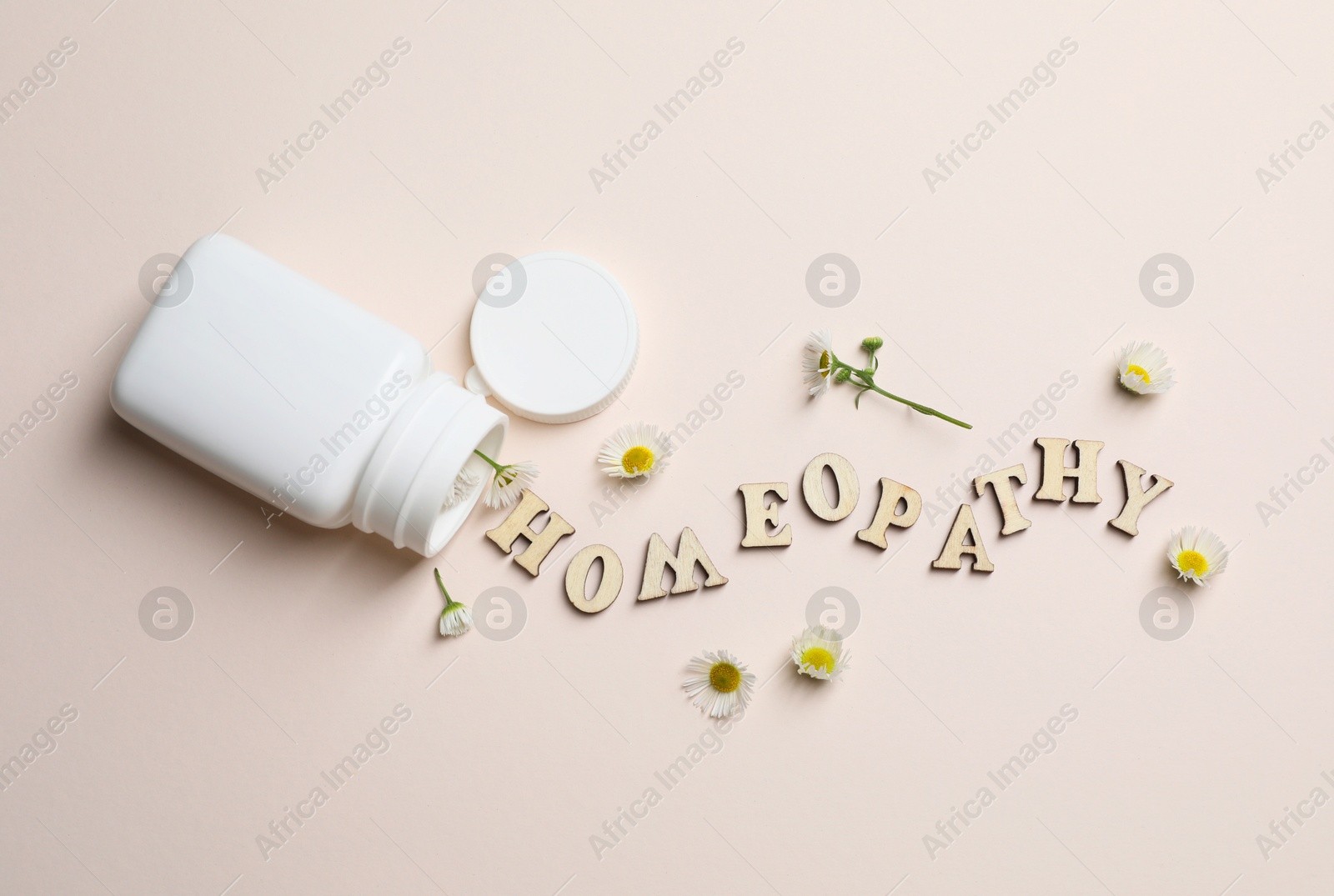 Photo of Word Homeopathy, plastic bottle and chamomiles on beige background, flat lay