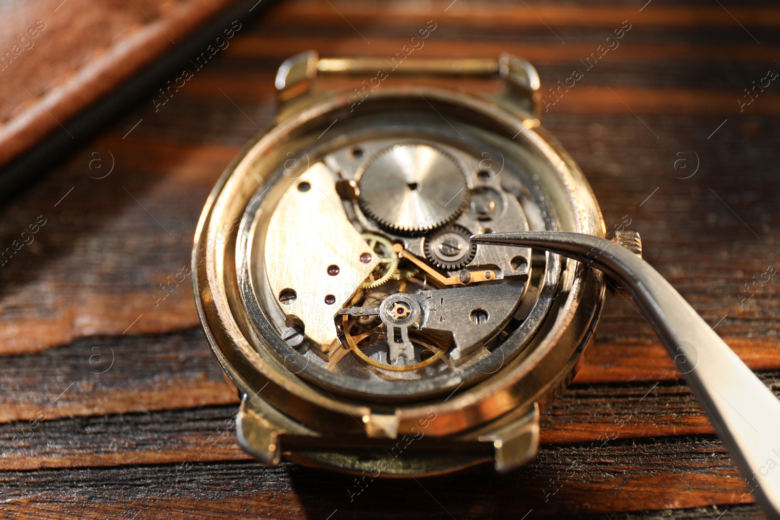 Photo of Mechanism of vintage wrist watch and tool on wooden table, closeup