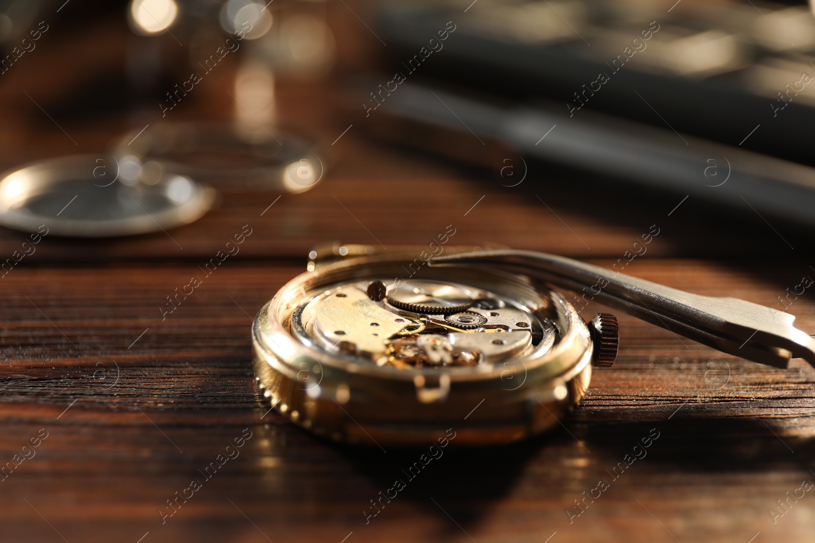 Photo of Mechanism of vintage wrist watch and tool on wooden table, closeup