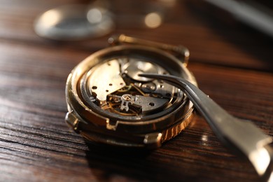 Photo of Mechanism of vintage wrist watch and tool on wooden table, closeup