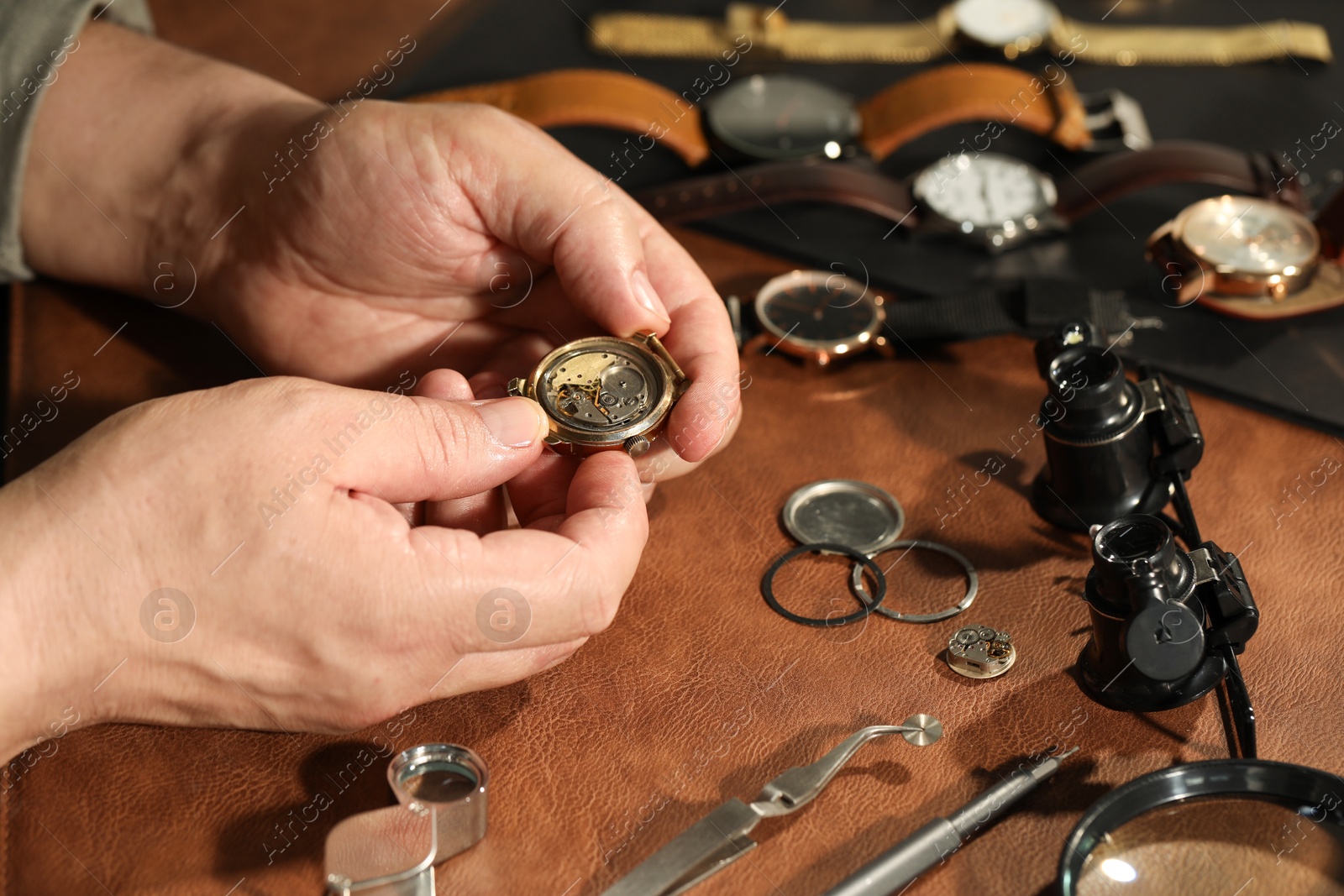 Photo of Man with mechanism of vintage wrist watch at table, closeup