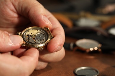 Photo of Man with mechanism of vintage wrist watch at table, closeup