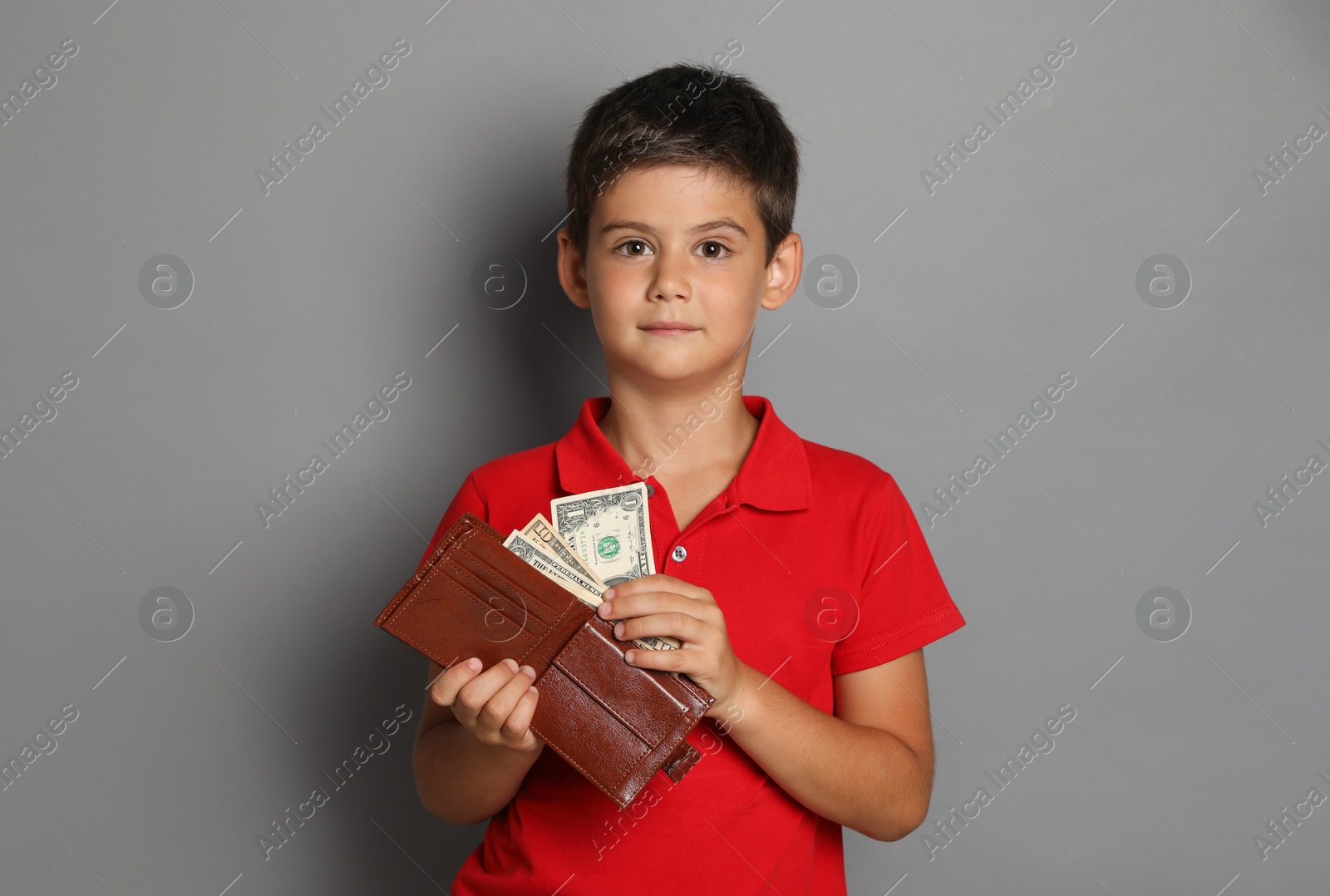 Photo of Cute boy with wallet and pocket money on grey background